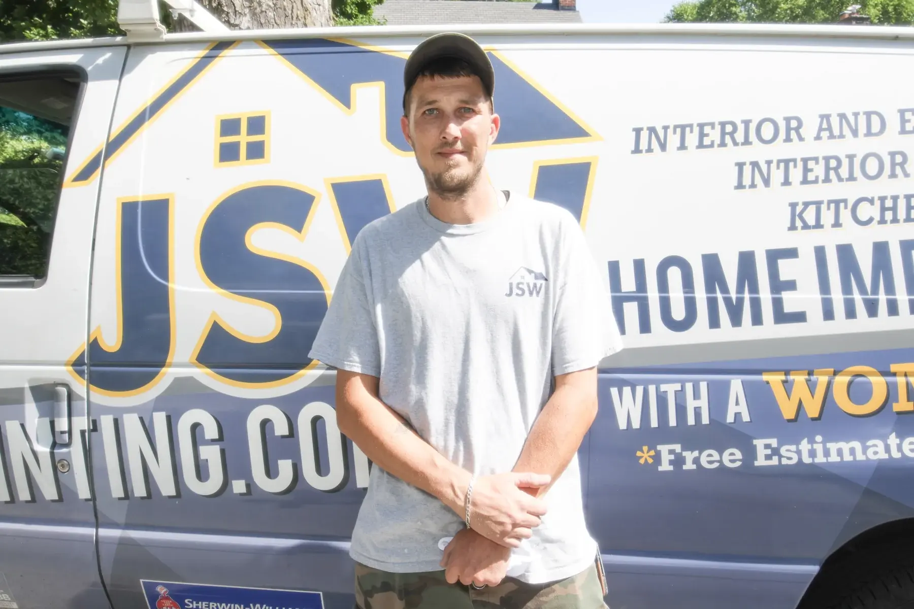 JSW crew member in a gray company shirt standing in front of a branded JSW work van