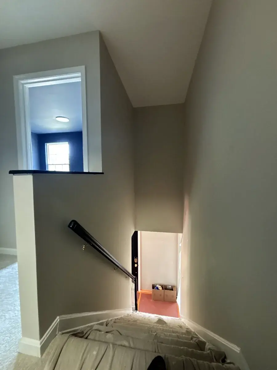 Light neutral stairwell with dark handrail and clean trim transitions