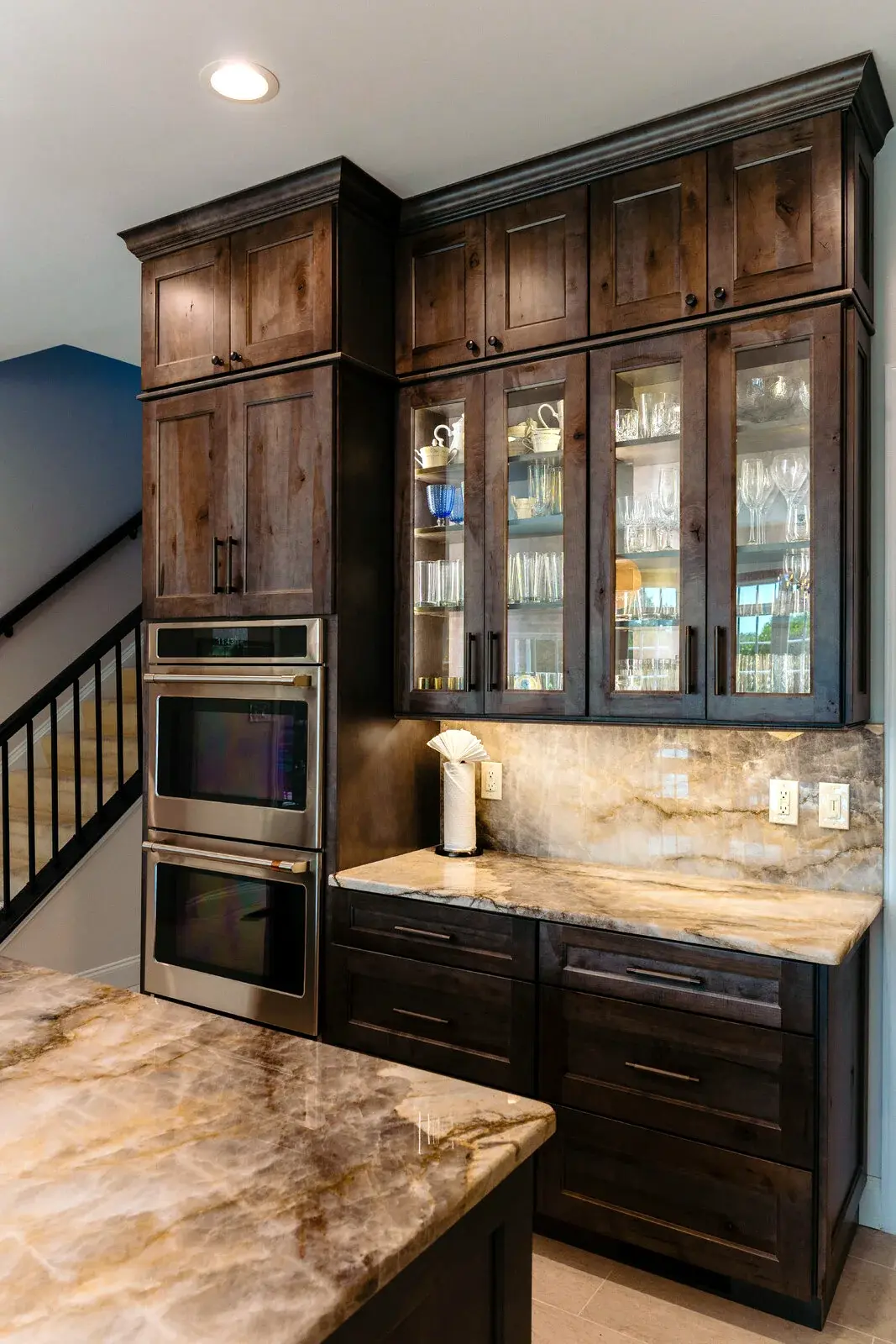 Tall custom wood cabinetry with integrated appliances and display lighting