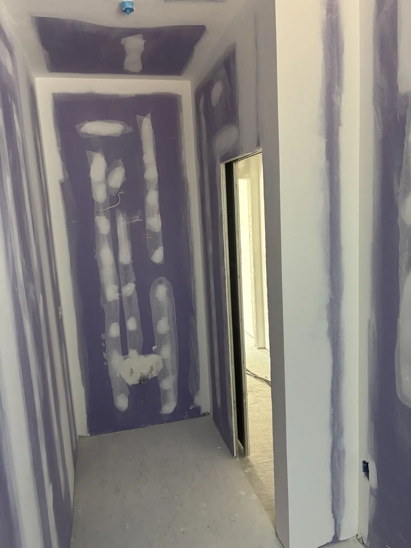 Drywall repair patch being fitted and blended into the surrounding wall