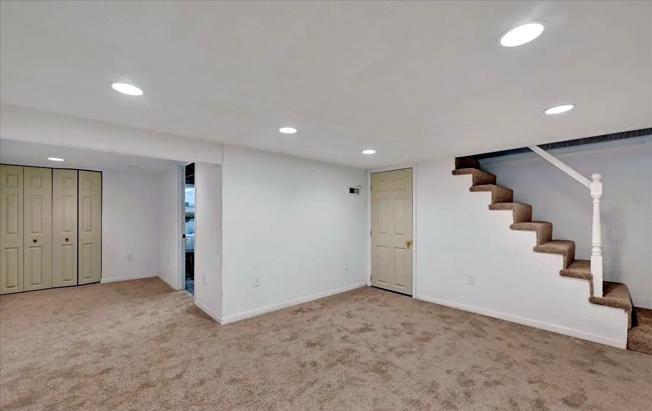 Finished lower-level room with new carpet and an open stair connection