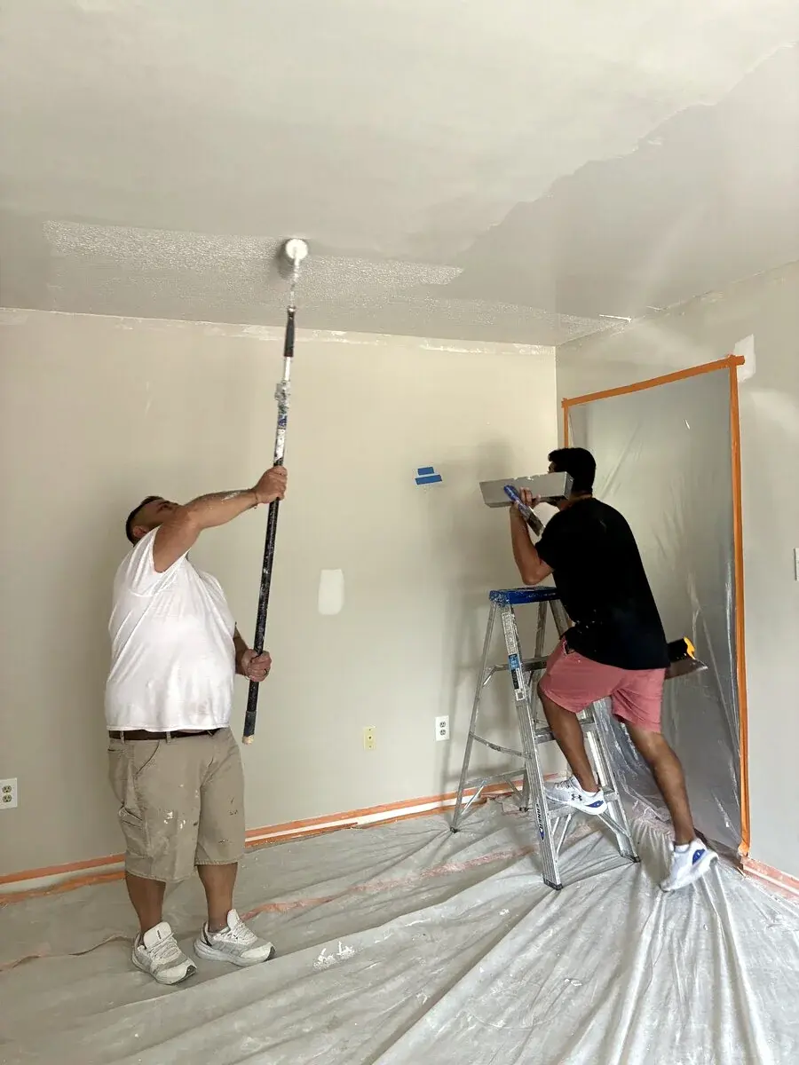 JSW crew painting interior walls and a ceiling in a carefully protected room