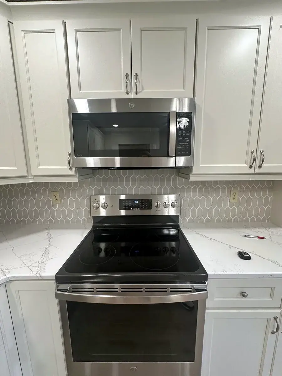 Finished kitchen with aligned hex tile backsplash between cabinetry and counters