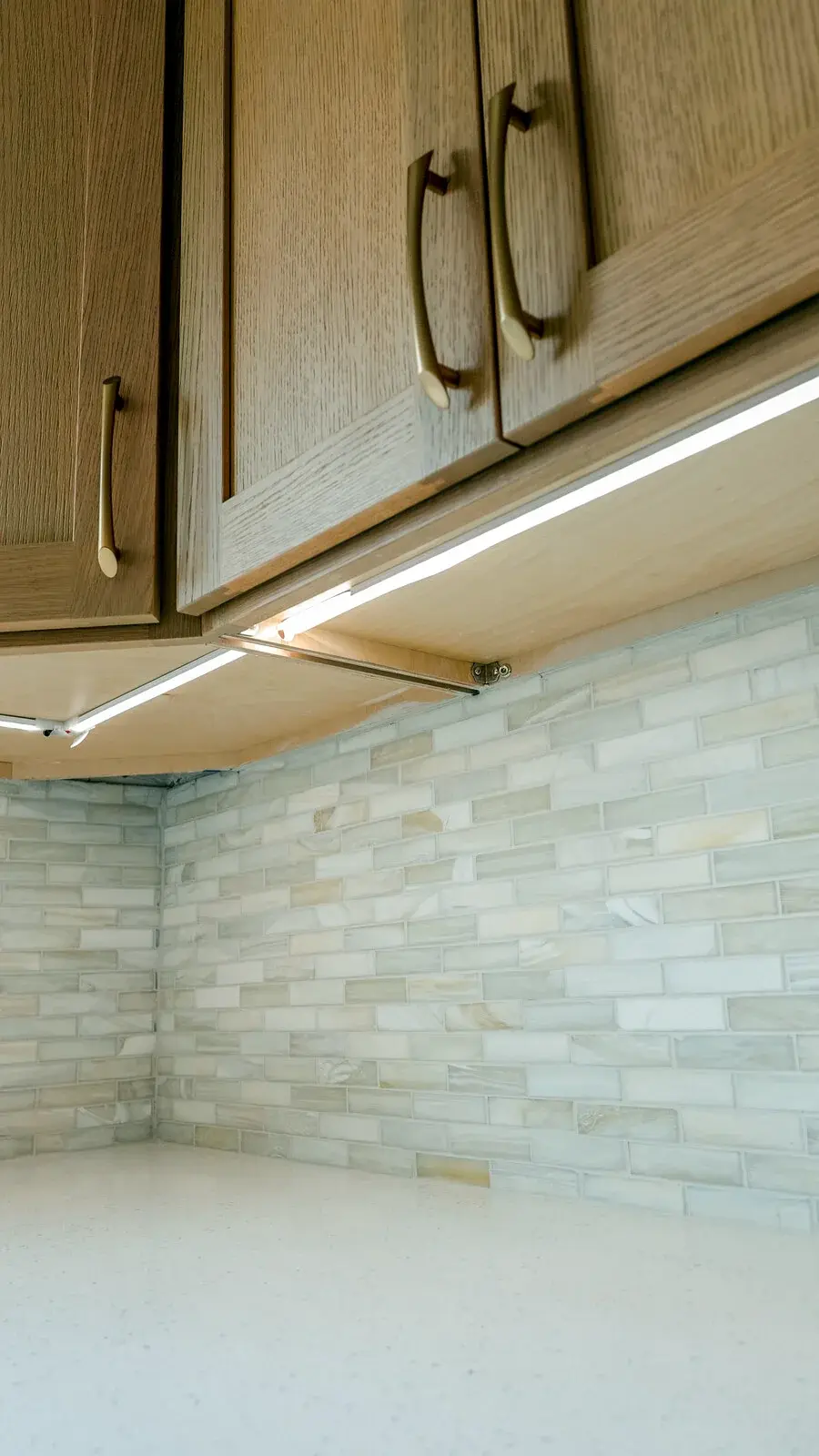 Neutral stacked tile backsplash beneath natural wood cabinets