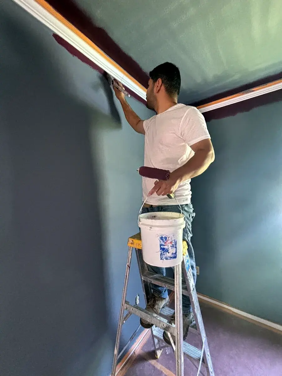 Painter cutting in along ceiling and trim edges