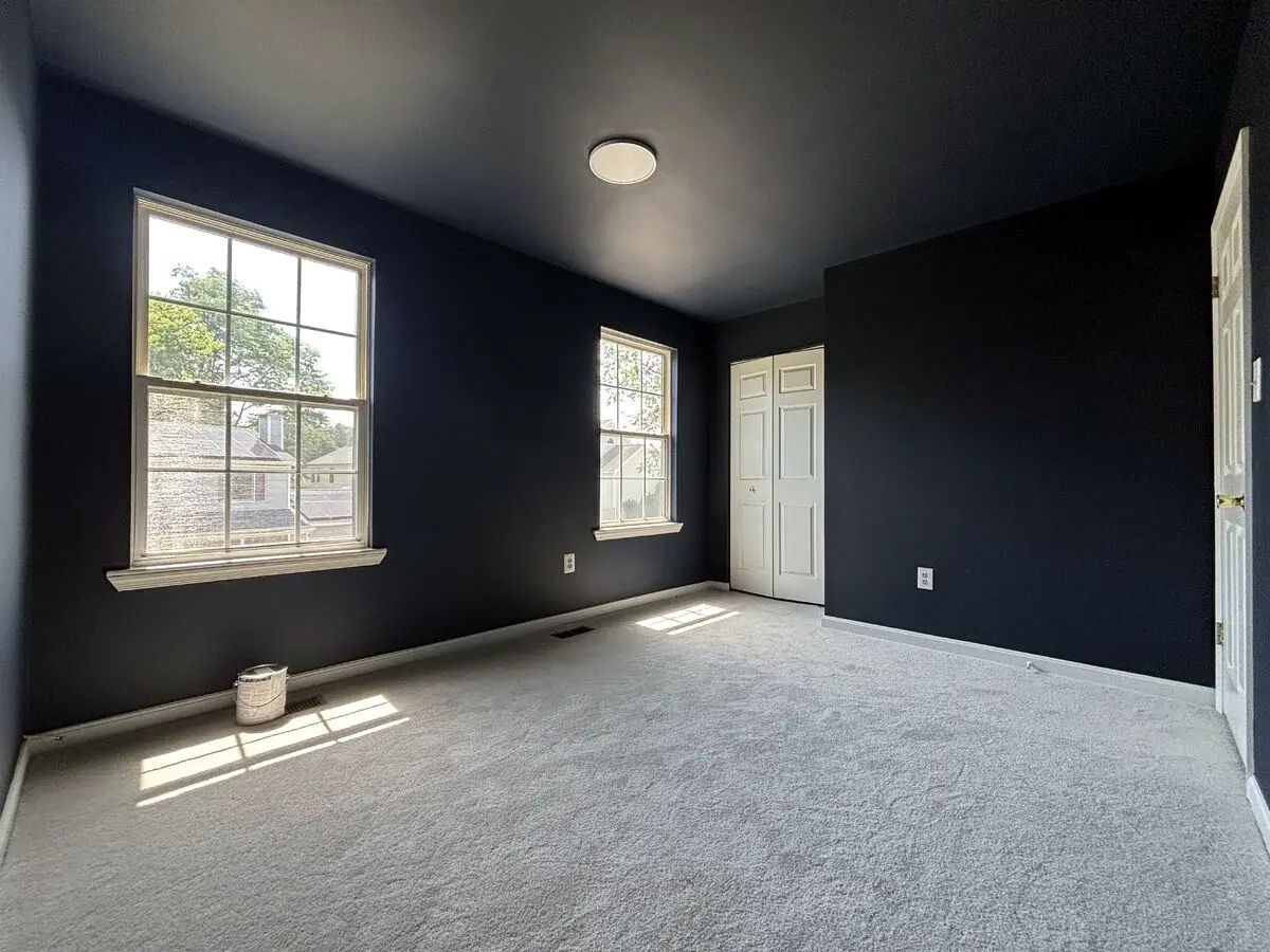 Wide view of a finished navy bedroom with bright trim