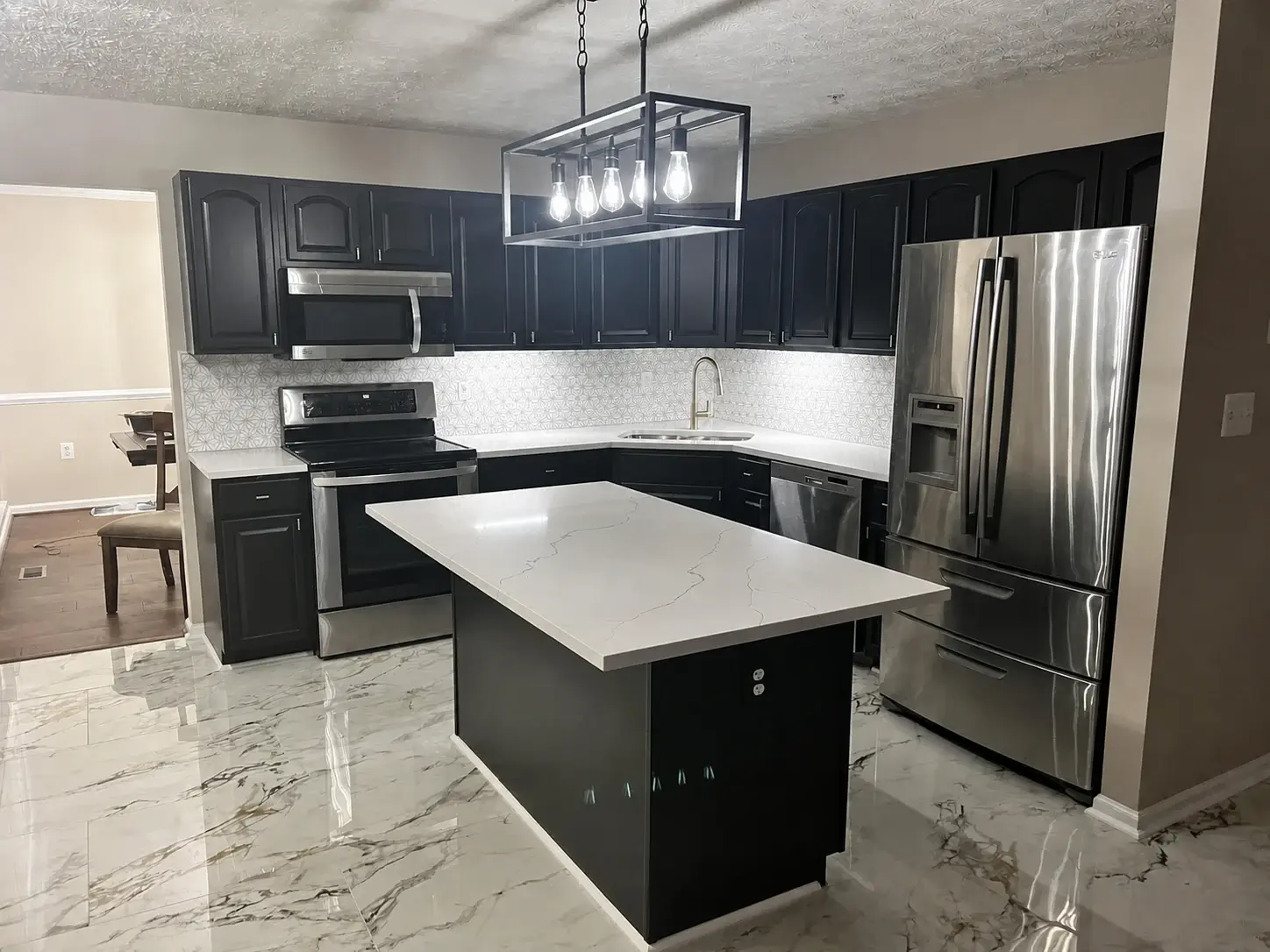 Finished black and white kitchen with painted cabinetry, bright island, and coordinated counters