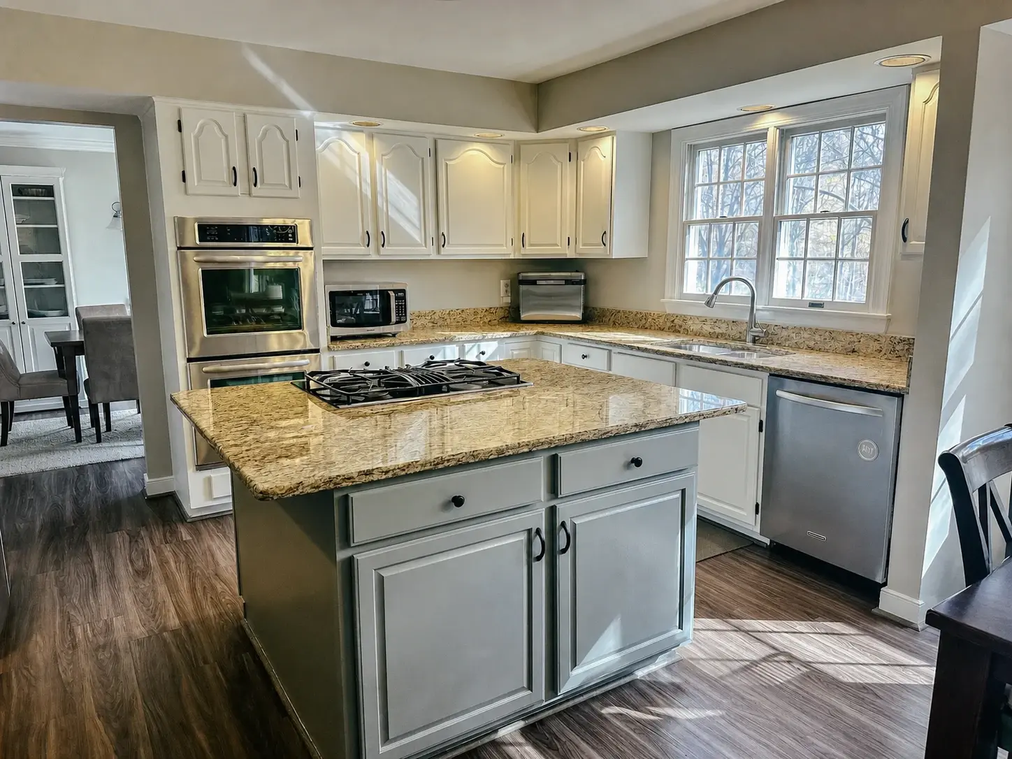 Finished painted kitchen with light cabinetry, island seating, and coordinated counters