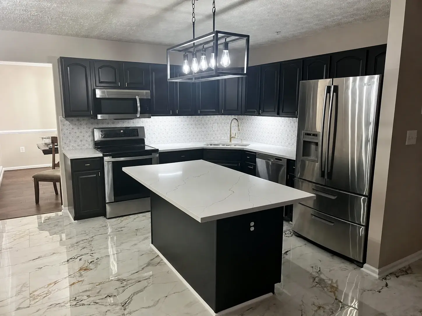 Finished black and white kitchen with a painted dark island and bright surrounding cabinetry