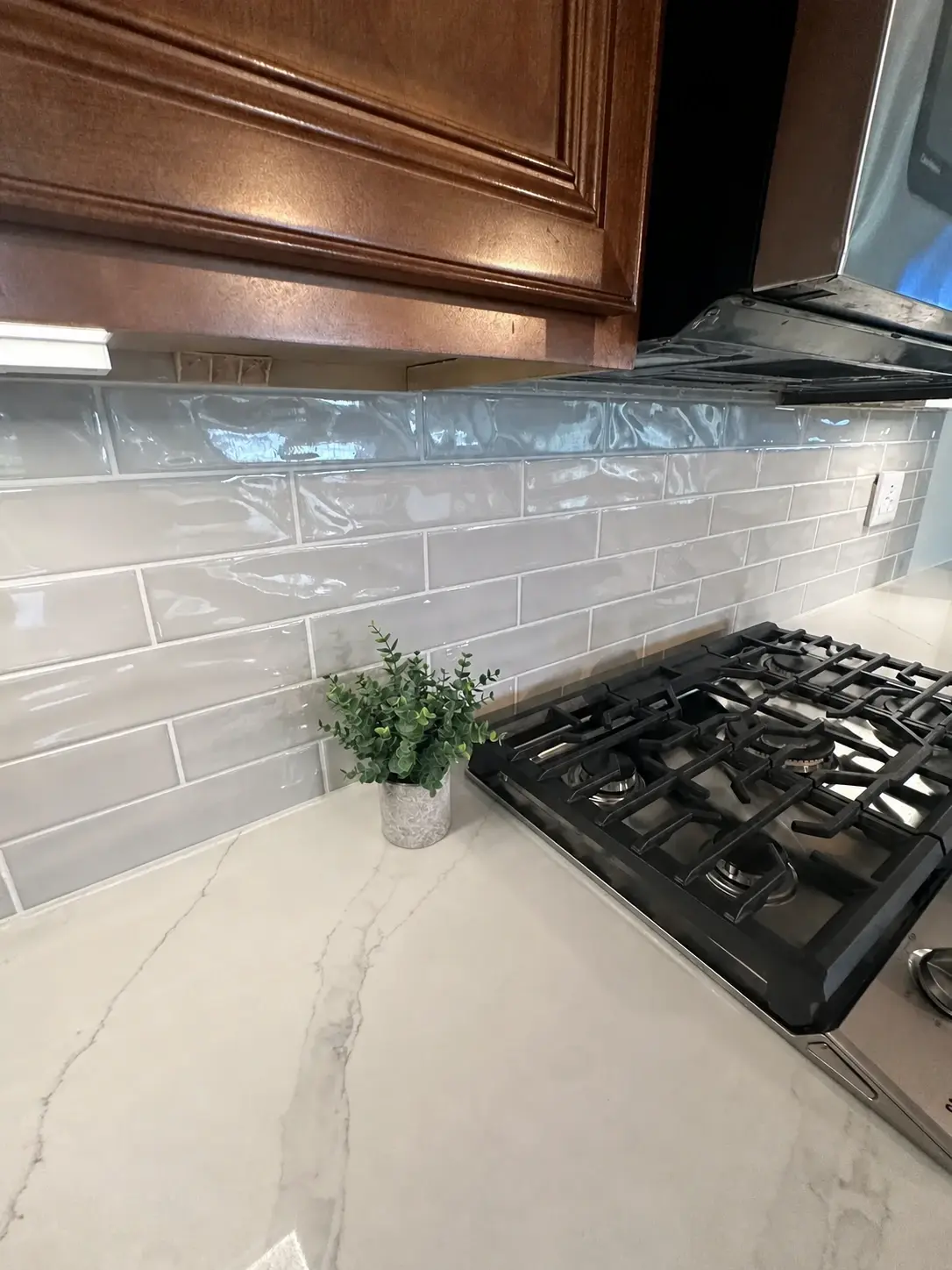 Finished glossy kitchen backsplash with aligned grout lines and clean cabinet transitions
