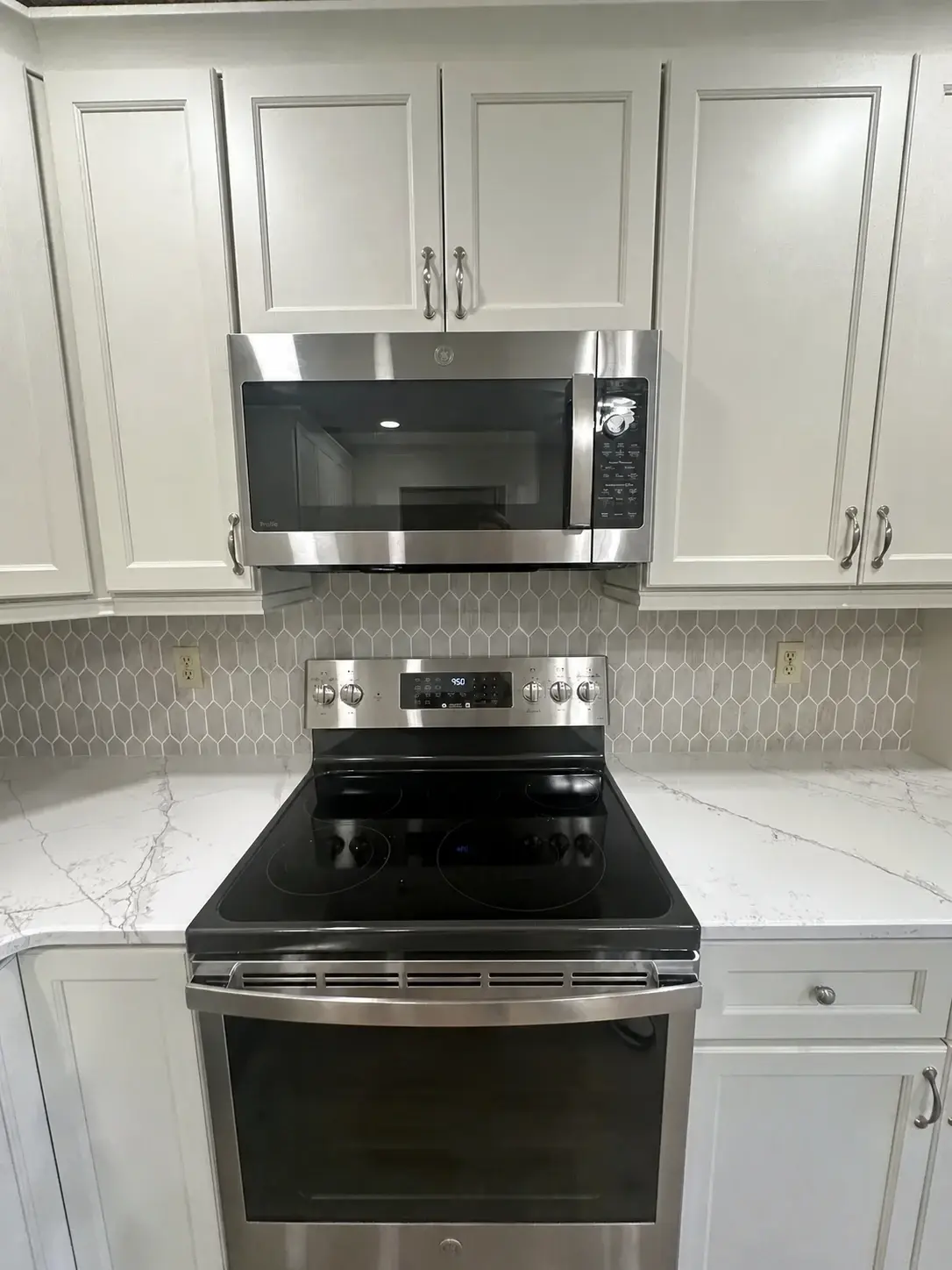 Finished kitchen with aligned hex tile backsplash between cabinetry and counters