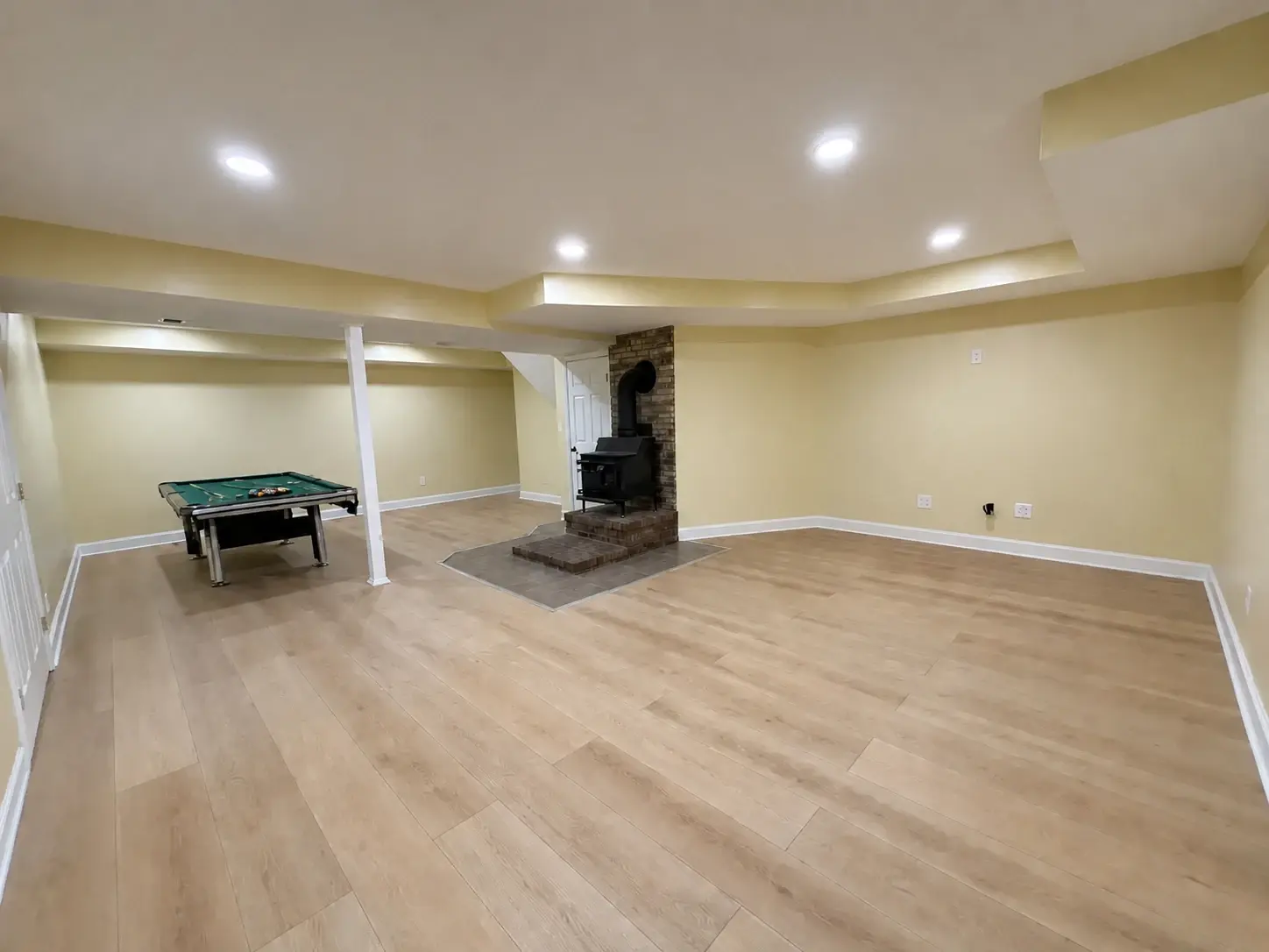 Finished basement recreation room with an open playable pool table, recessed lighting, and a central fireplace