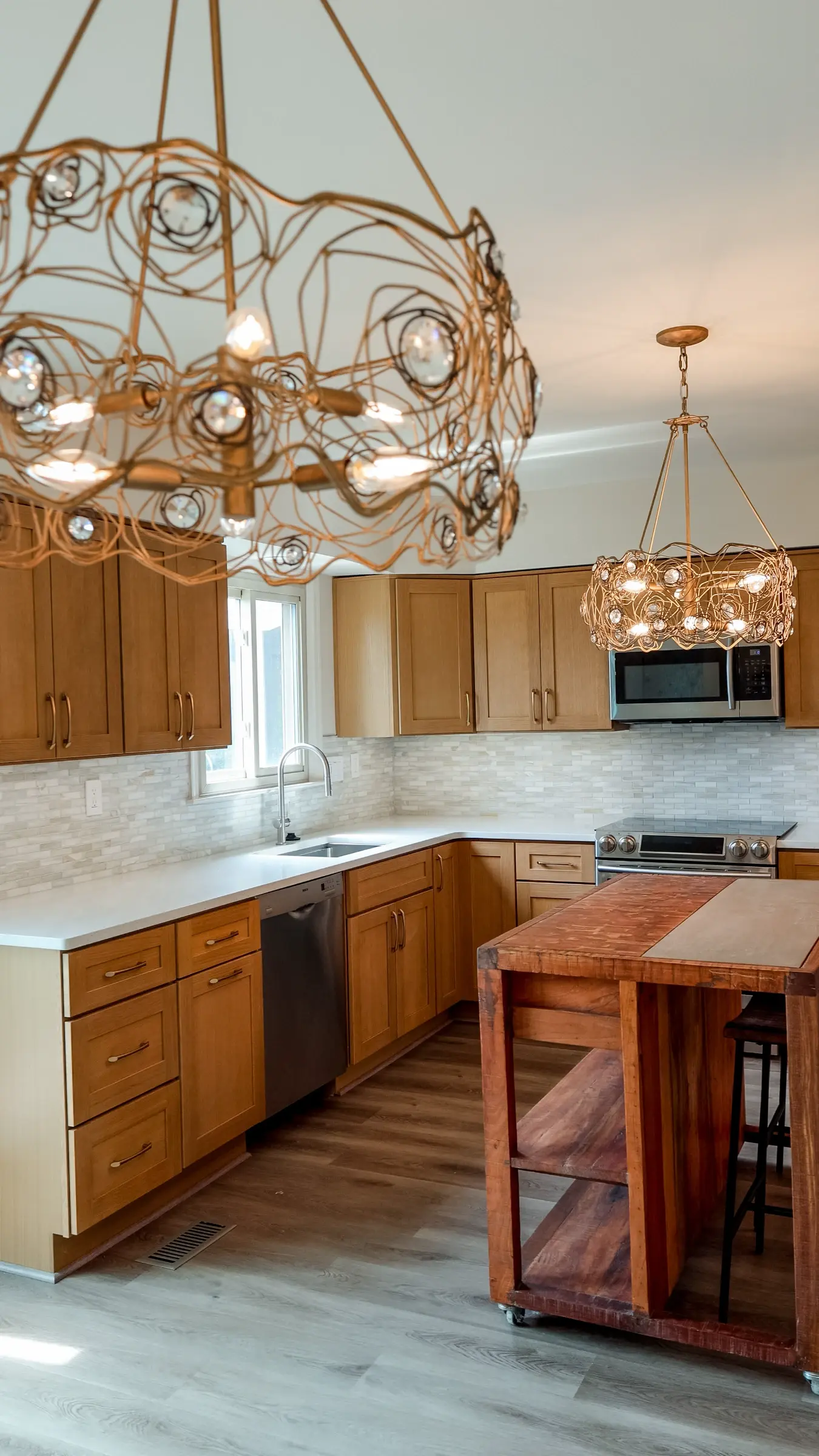 Finished natural-wood kitchen with two islands, stone counters, and layered pendant lighting