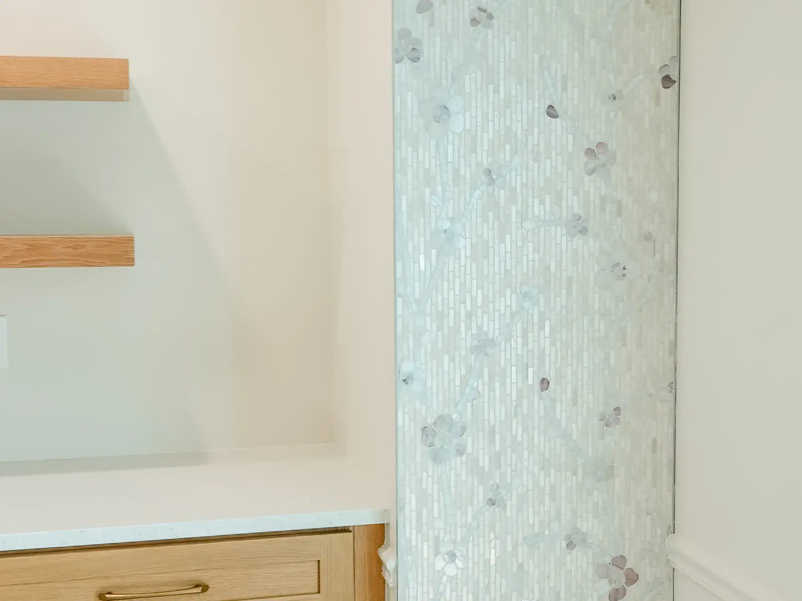Finished bathroom with a pale mosaic tile shower feature and fitted shelves