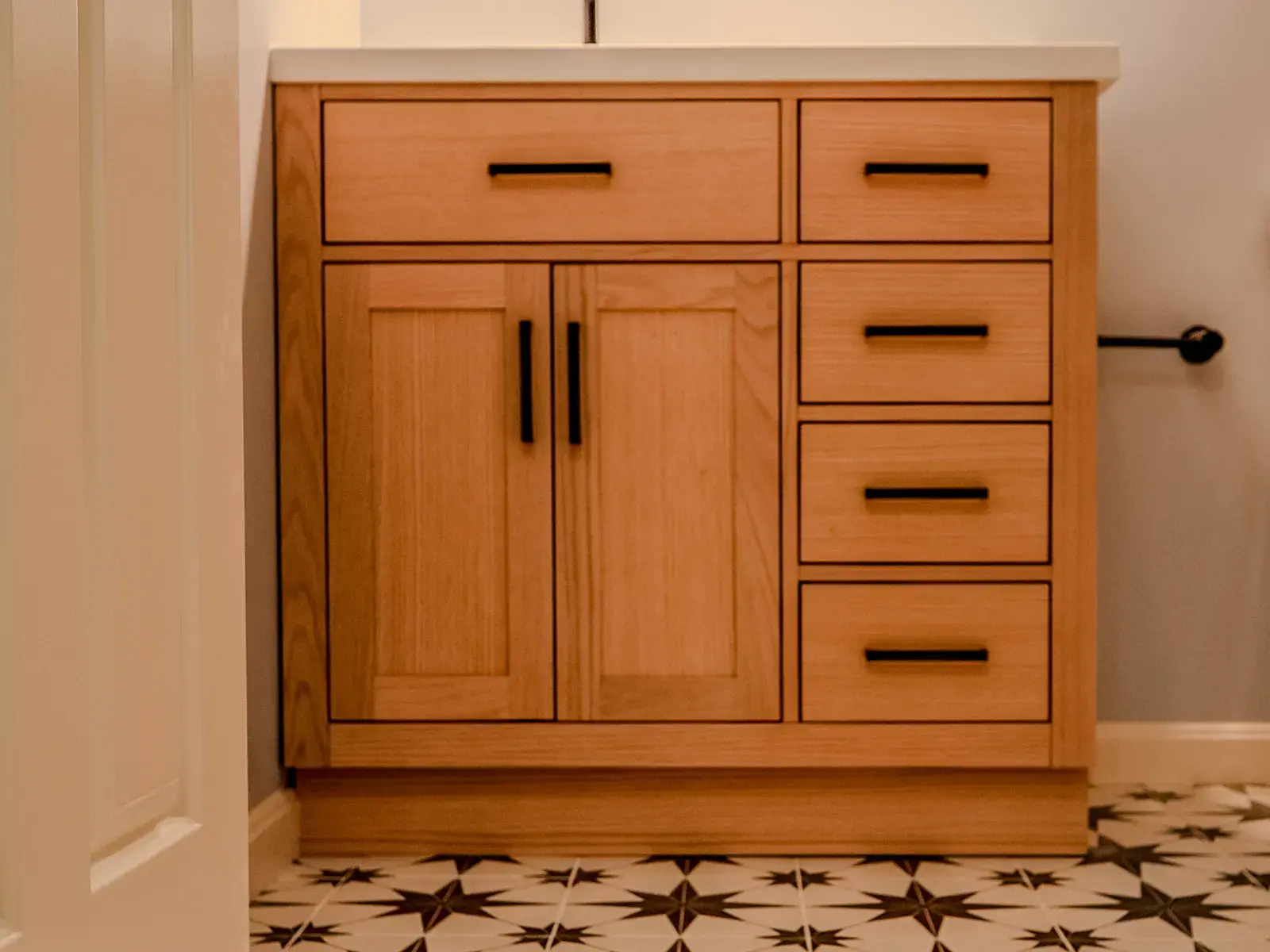 Finished bathroom with a warm wood vanity, patterned floor tile, and clean wall finish