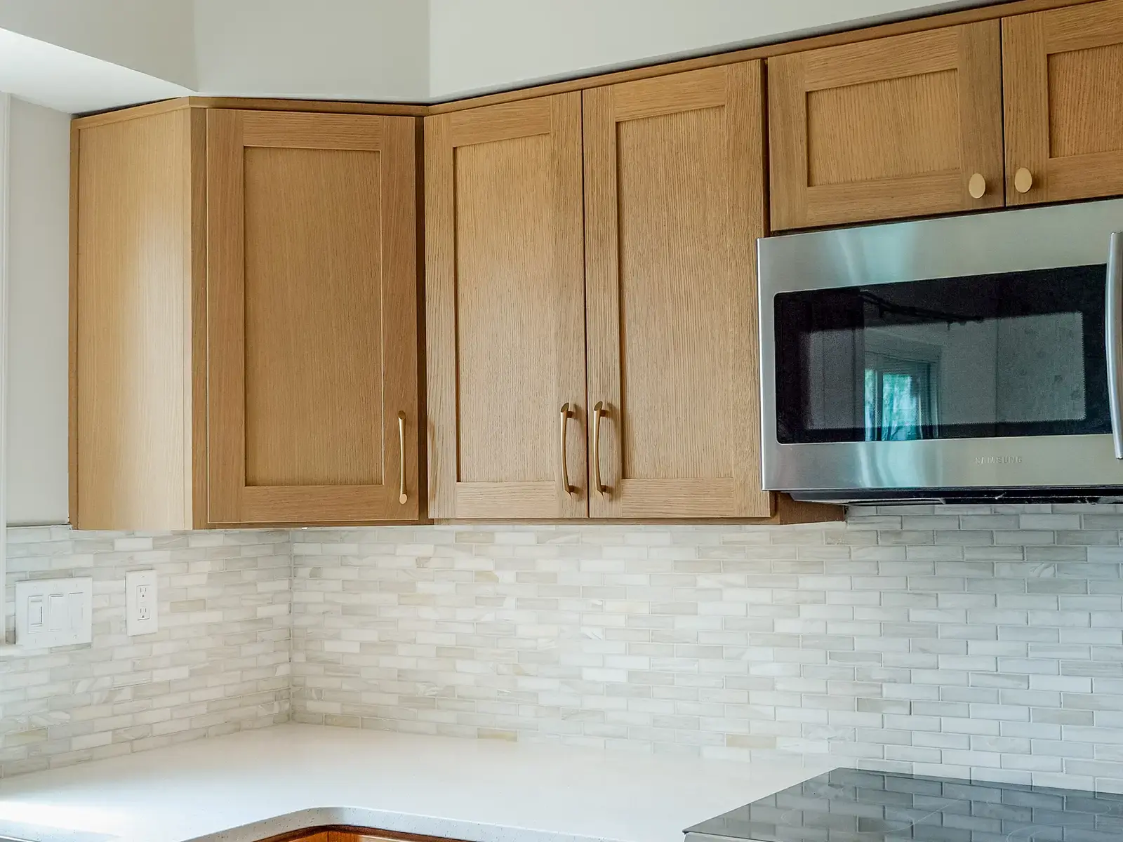 Finished kitchen corner with warm wood cabinets and a mosaic backsplash