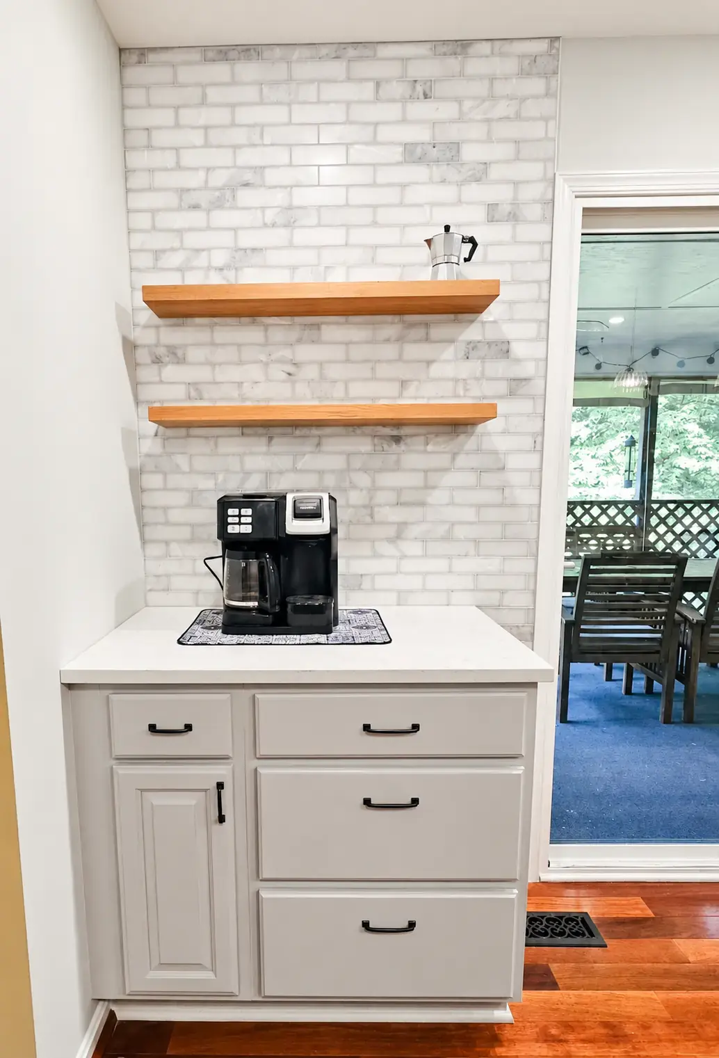 Finished coffee station with marble-look subway tile extending from the counter to the ceiling around floating shelves
