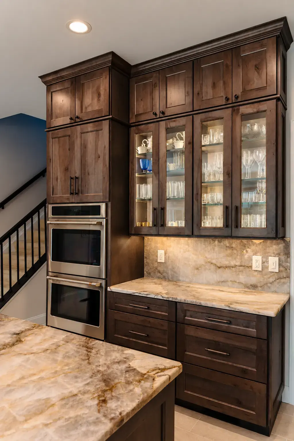 Dark wood storage wall with glass-front upper doors, tall cabinetry, and integrated appliances