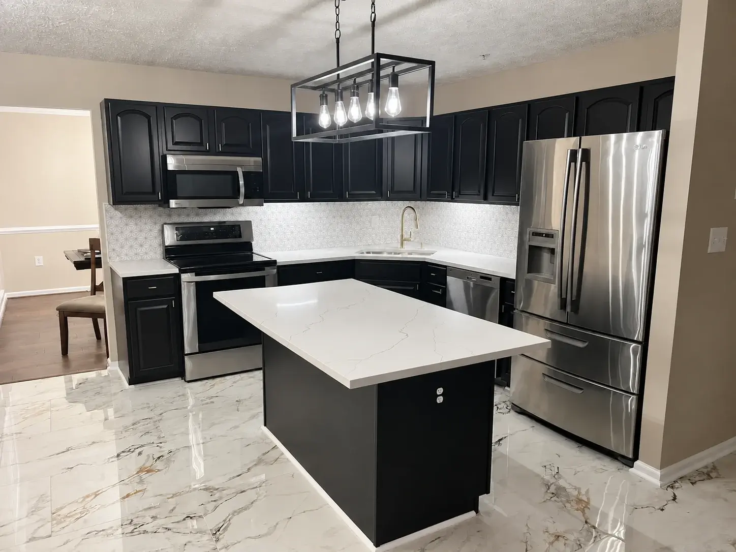 Black-and-white kitchen with glossy marble-look floor tiles laid around a central island