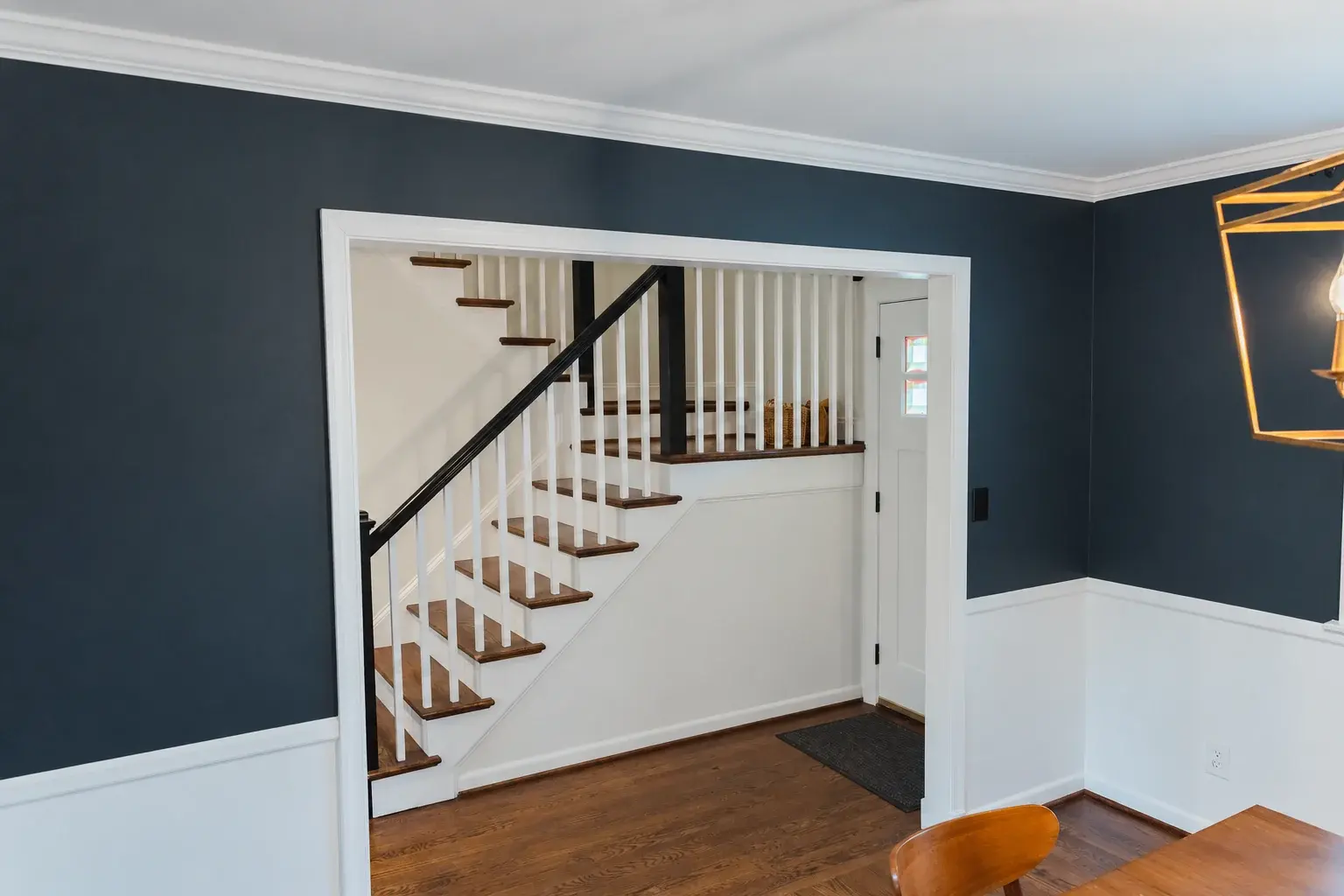 Dark painted room with a wide white-trimmed opening framing the stair hall beyond