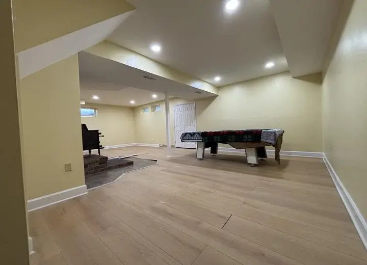 Finished lower-level living area with completed walls, flooring, lighting, and comfortable seating
