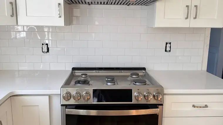 Kitchen range framed by white cabinets and white subway tile