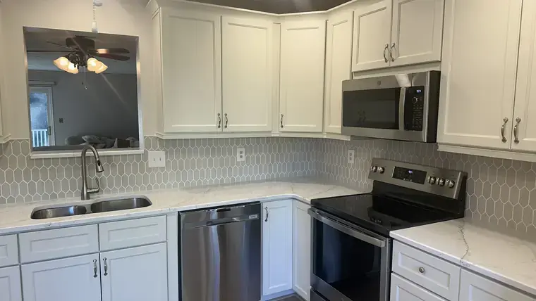 White kitchen cabinets with hex tile backsplash and stainless appliances