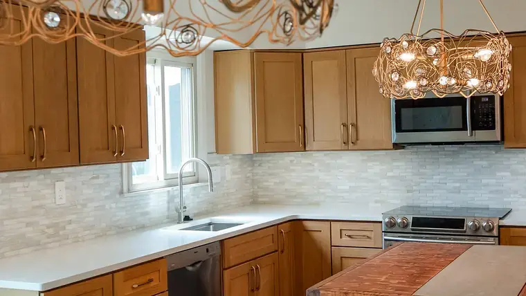 Warm wood kitchen cabinets, stone counters, and sculptural pendant lighting