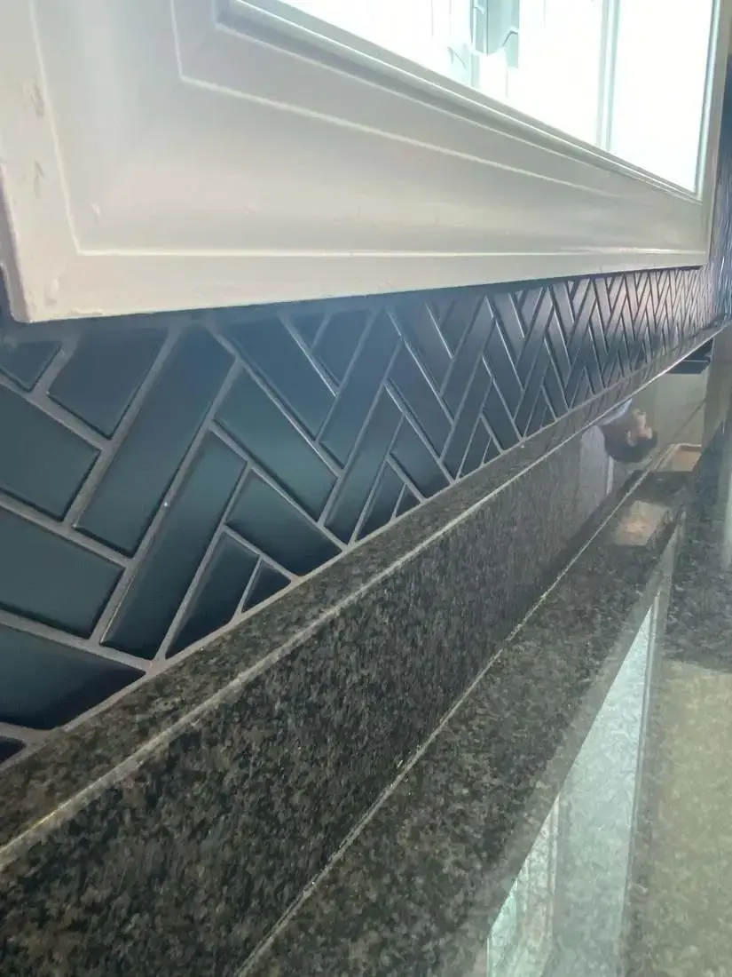 Blue herringbone backsplash aligned beneath a kitchen window