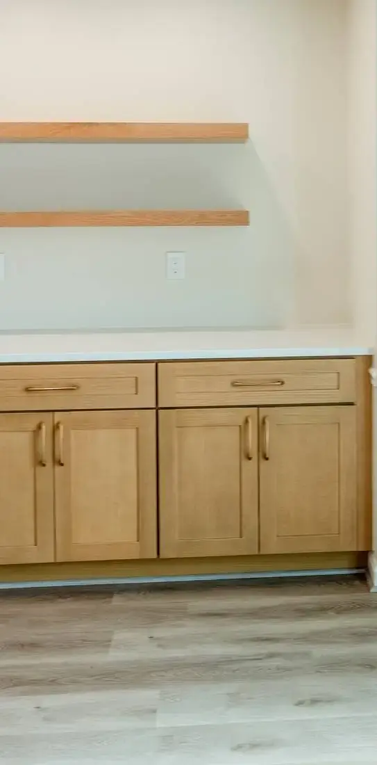 Natural base cabinetry with open wood shelves and a light tile wall