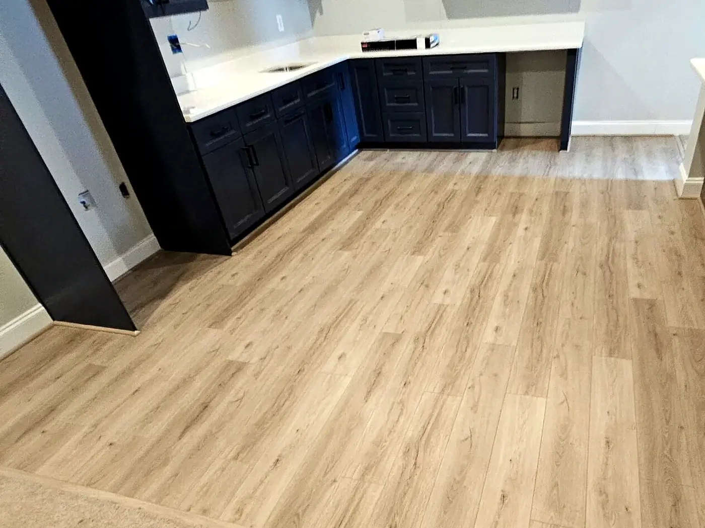 Cropped basement wet-bar flooring transition focused on cabinetry, durable floor, and nearby carpet