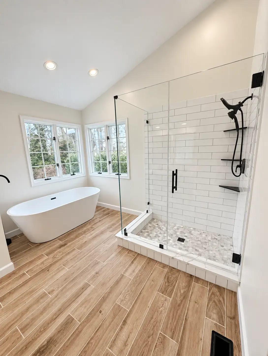 Finished bathroom with bright shower wall tile, pebble shower floor, tub, and floor tile in room context