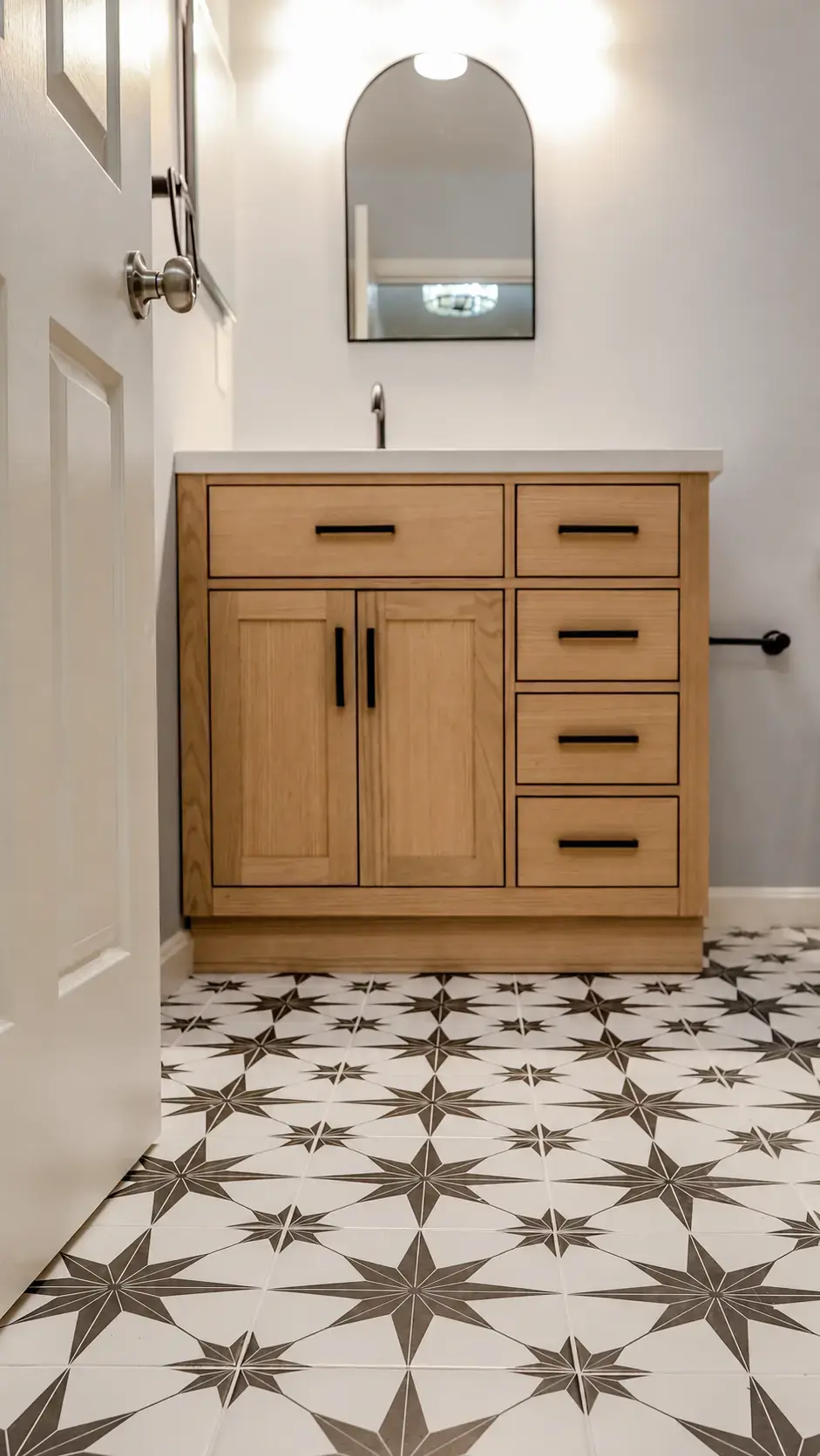 Finished powder room with a patterned tile floor shown in full room context