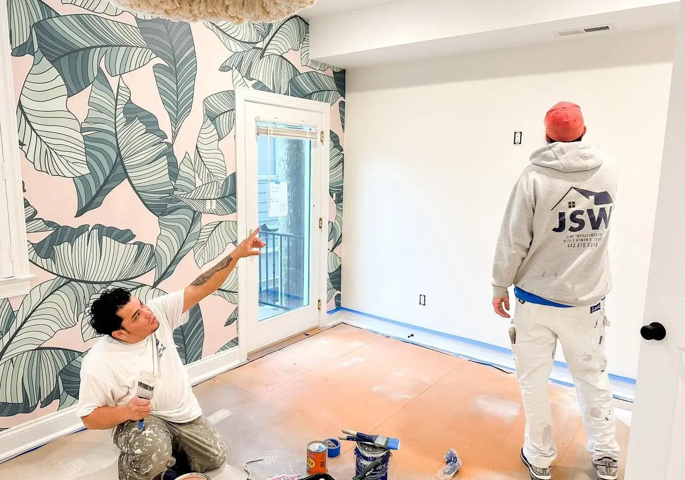 JSW crew aligning botanical wallpaper around a window during installation