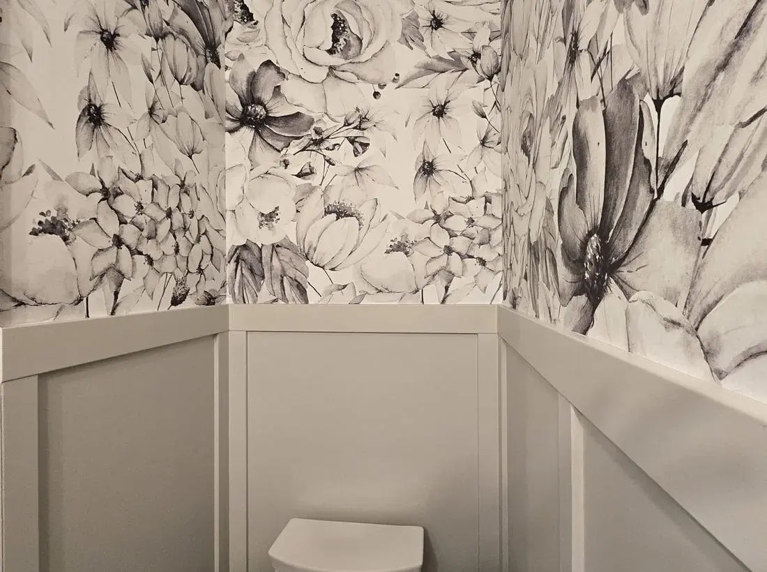 Finished powder room with bold floral wallpaper above painted wainscot