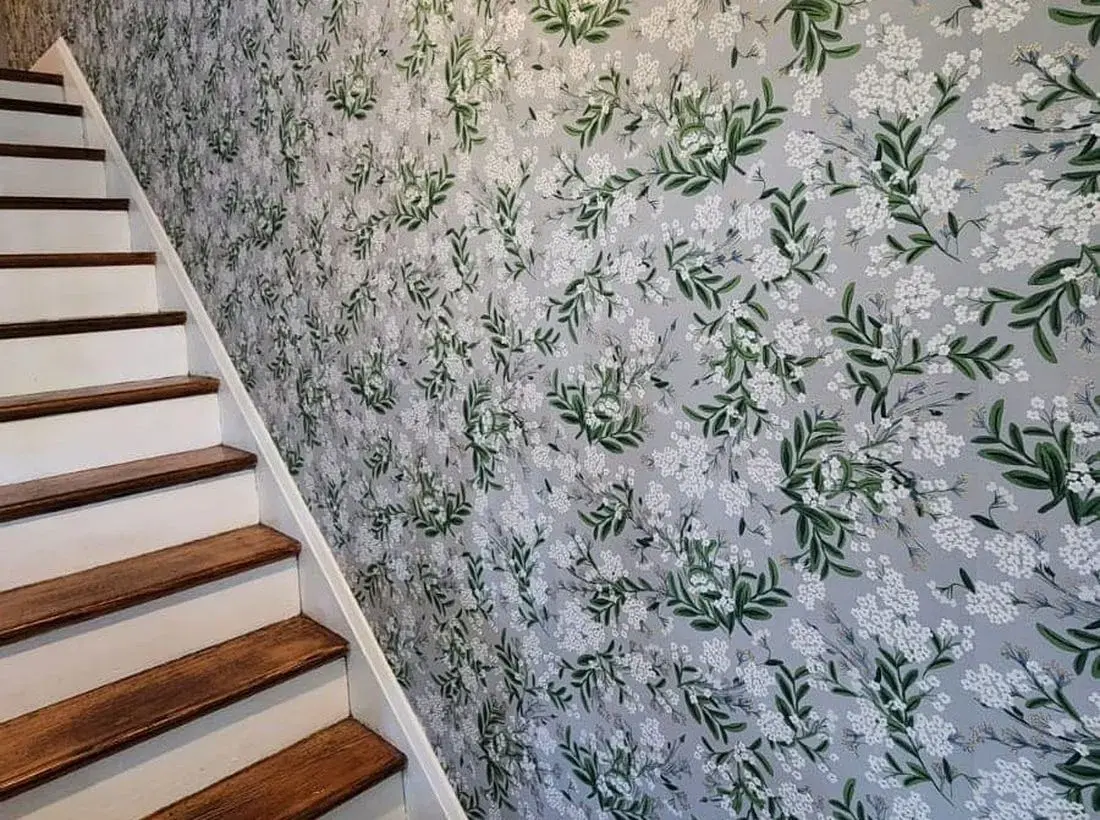 Finished botanical wallpaper installed along a tall stairway wall